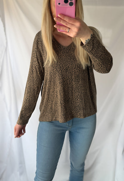 Eine Frau mit langen blonden Haaren macht ein Spiegel-Selfie in einem schicken Feinraummode Leo Pullover Damen Animalprint aus 20% Angorawolle, gepaart mit hellblauen Jeans, und posiert vor einem weißen Stoffhintergrund.