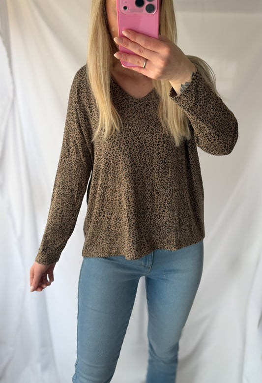 Eine Frau mit langen blonden Haaren macht ein Spiegel-Selfie in einem schicken Feinraummode Leo Pullover Damen Animalprint aus 20% Angorawolle, gepaart mit hellblauen Jeans, und posiert vor einem weißen Stoffhintergrund.