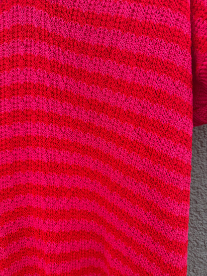 Die Nahaufnahme des Feinraummode Sommerliches Strickkleid mit Streifen pink zeigt die horizontalen rot-rosa Streifen und das strukturierte Strickmuster, das jeden leuchtenden Farbton des Garns betont.