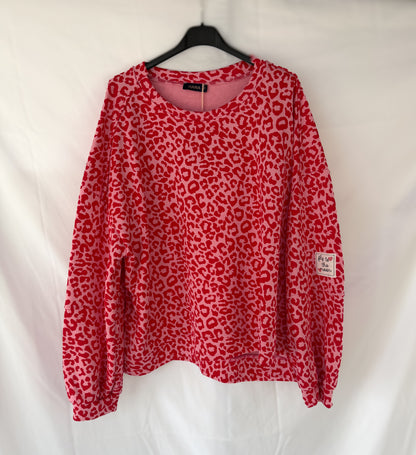 Das Oversize Sweatshirt im Leoparden Look - rot von Feinraummode hängt an einem schwarzen Bügel vor weißem Hintergrund und ist der perfekte trendige Pullover für Damen.