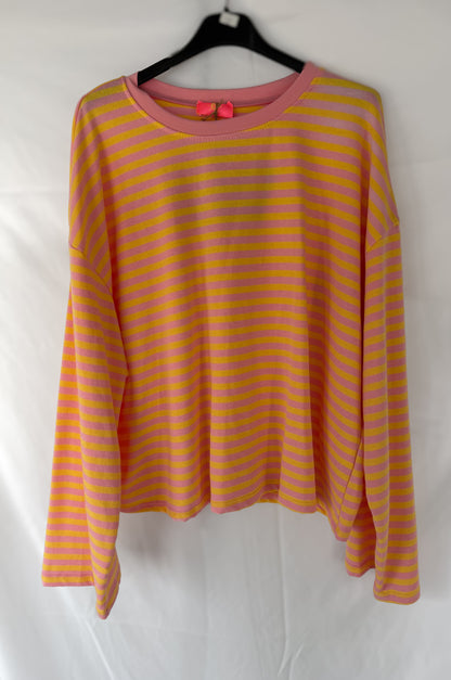 Das Good Vibes Streifen Longsleeve von Feinraummode hat rosa und gelbe Streifen, einen rosa Ausschnitt und eine süße Schleife auf dem Rücken. Auf einem schwarzen Bügel vor weißem Hintergrund präsentiert, ist es perfekt für deine Frühlingsmode-Garderobe.