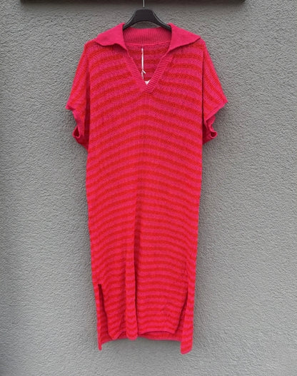 Das "Sommerliches Strickkleid mit Streifen pink" von Feinraummode ist ein locker geschnittenes, kurzärmeliges Kleid mit feinen Rot-Pink-Streifen, V-Ausschnitt und weitem Polokragen und hängt an einem schwarzen Bügel vor grauer Wand.