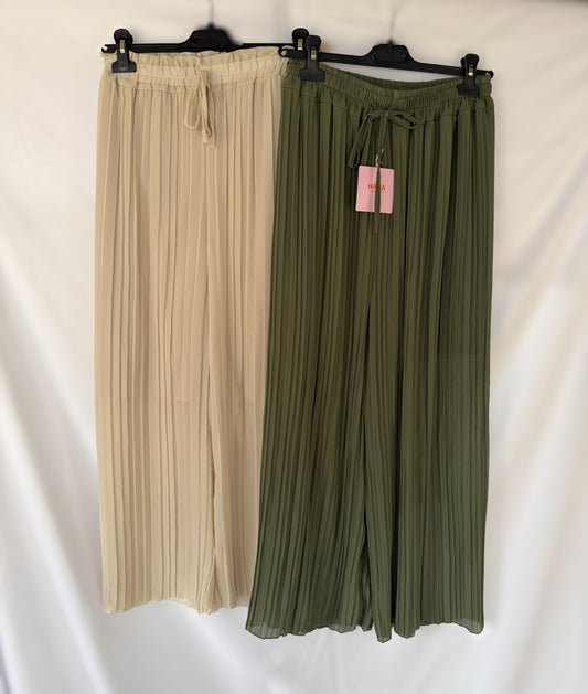 Zwei Paar Feinraummode Plissee-Hosen Amanda mit weitem Bein hängen auf schwarzen Bügeln vor weißem Hintergrund - eine beige, eine olivgrün. Beide haben einen elastischen Bund mit Kordelzug.