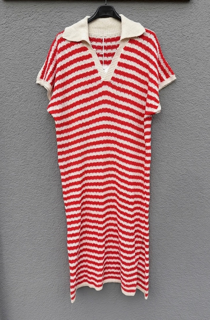 Das sommerliche Strickkleid mit roten Streifen von Feinraummode hängt an einem schwarzen Bügel vor einer grauen, strukturierten Wand.